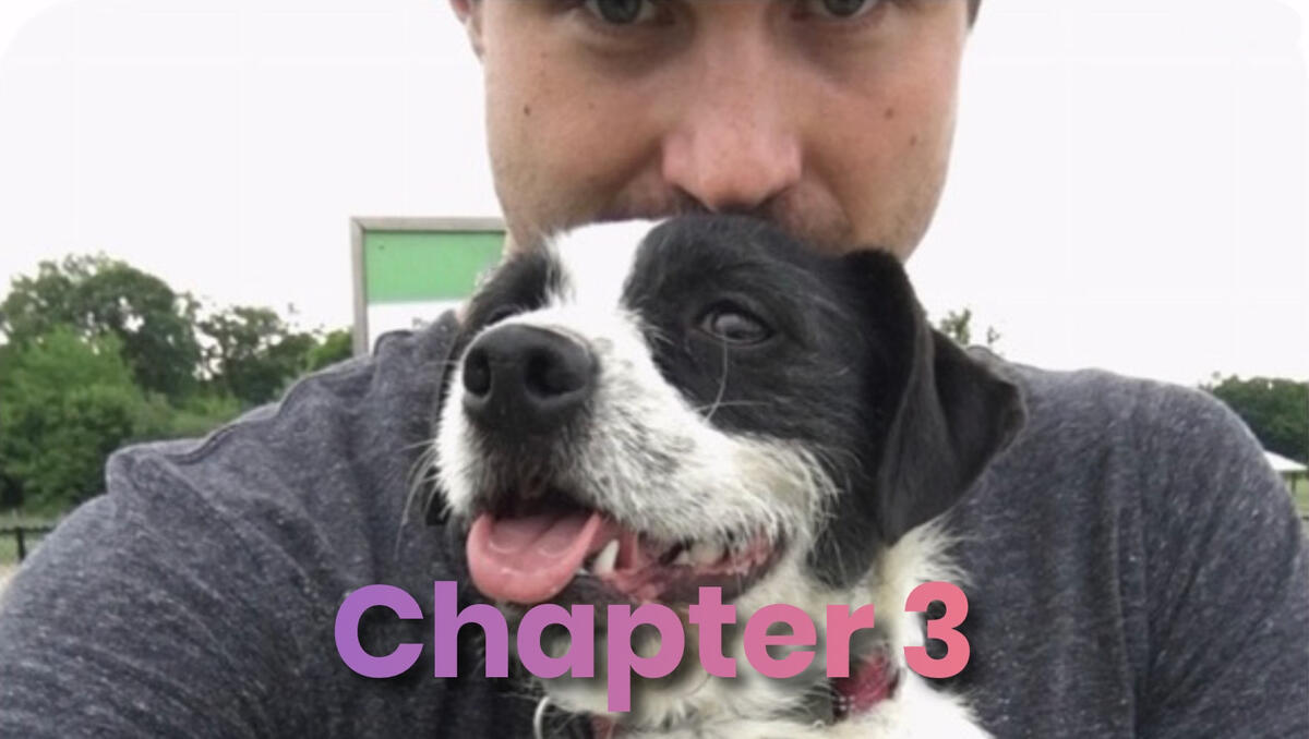 A man smiling while holding a black and white dog