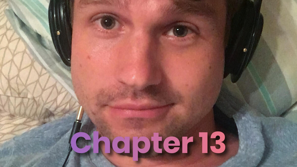 Close-up selfie of Damien wearing headphones in bed