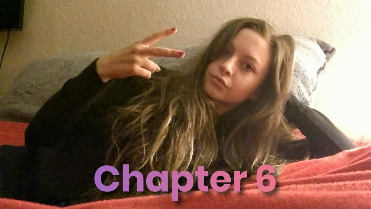 A woman lying on a bed making a peace sign with her hand.